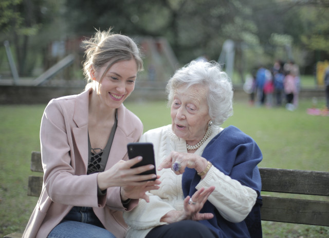 Jovem mostra emprego a cuidar de idosos num telemóvel a senhora de cabelos brancos.