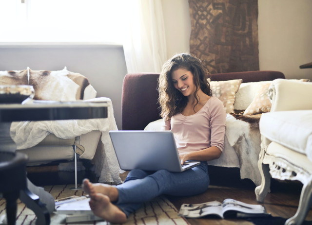 Mulher jovem a trabalhar online no computador enquanto sorri.