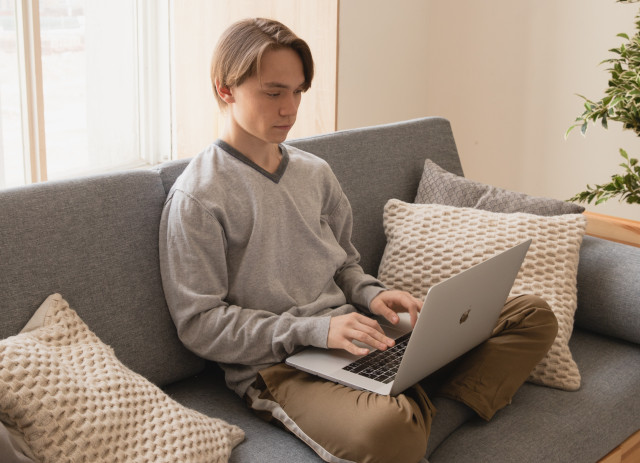 Jovem sentado no sofá a pesquisar no computador como conseguir experiência profissional.