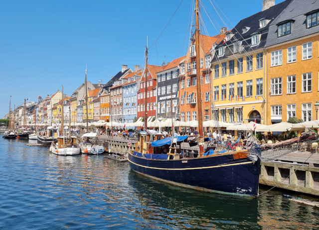 Imagem de canal com barco e prédios coloridos em Copenhaga, Dinamarca, a primeira das melhores cidades do mundo para trabalhar.