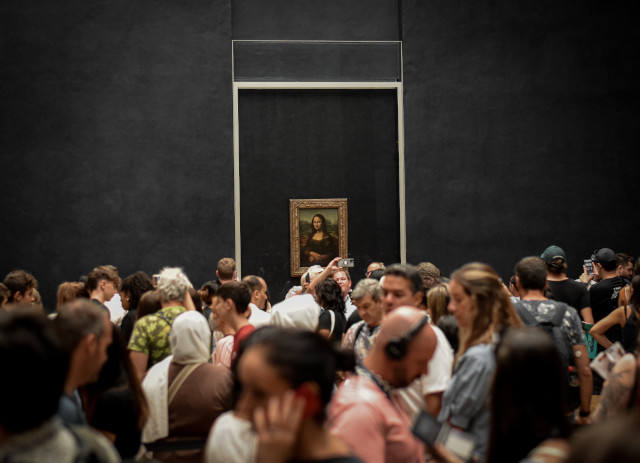 Quadro da Mona Lisa no Museu do Louvre a ser apreciado por muitas pessoas que adoram curiosidades sobre arte.