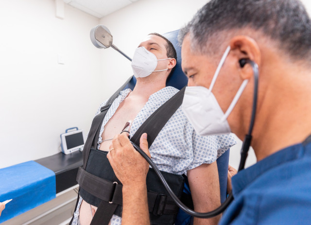 Médico cardiologista com máscara e auscultadores a analisar paciente num exemplo de uma das especialidades médicas mais bem pagas em Portugal.