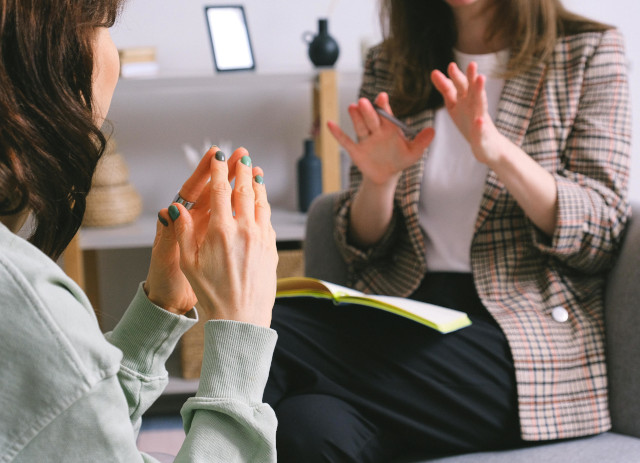 Duas mulheres a gesticularem, sem se lhes verem as mãos, durante conversa sobre cursos de Psicologia.