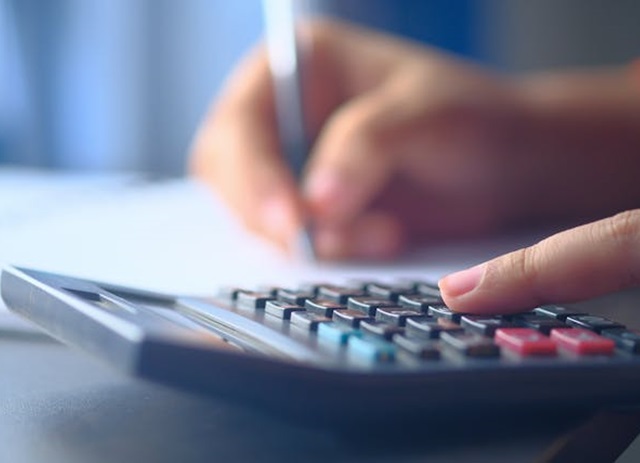 mulher usa calculadora e papel para calcular indemnização por despedimento
