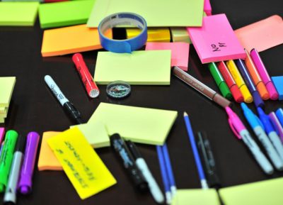 Lista de material escolar com canetas e post-its de várias cores.