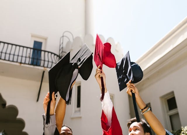 alunos universitários levantam chapéu de curso