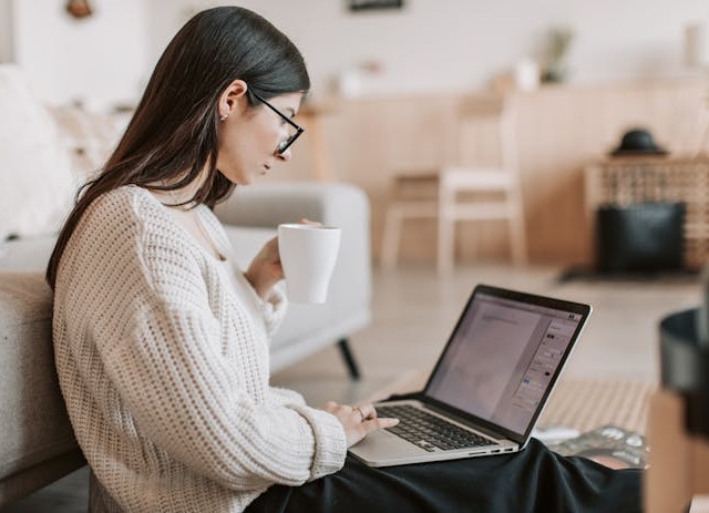 ghostwriter escreve ao computador enquanto segura uma caneca com outra mão