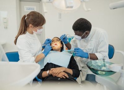 médico e assistente de medicina dentária realizam procedimento de saúde oral em mulher