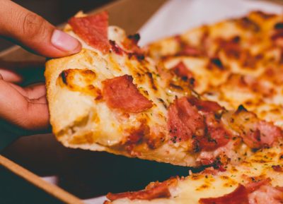 Mão a segurar uma fatia de pizza.